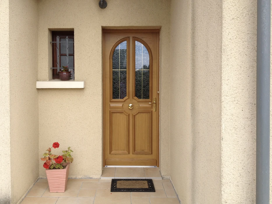 Façade extérieure d'habitation avec porte d'entrée en bois et fenêtre
